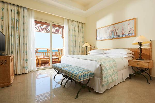 Schlafzimmer im Sheraton Soma Bay Resort mit Meerblick, Bett, Nachttischen und dekorativem Gemälde.
