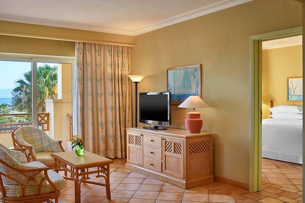 Innenansicht der Suite im Sheraton Soma Bay Resort mit Fernseher, Tisch, Sesseln und Blick auf das Meer.