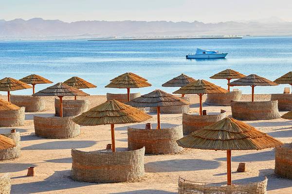 Strand des Sheraton Soma Bay Resorts mit vielen Strohschirmen und einer Yacht im Hintergrund