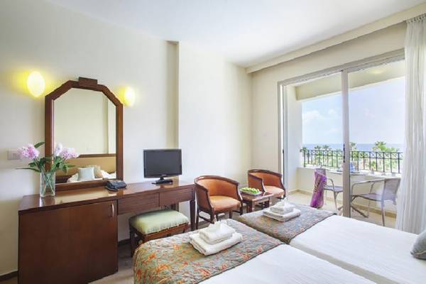 Doppelzimmer im Aquamare Beach Hotel & Spa mit zwei Betten, Schreibtisch und Meerblick.