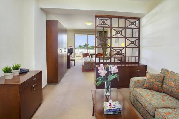 Innenbereich einer Suite im Aquamare Beach Hotel & Spa mit Wohnzimmer und Schlafzimmerbereich.