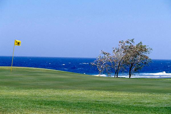 Golfplatz mit Blick auf das Meer und einer gelben Fahne auf der vierten Position.