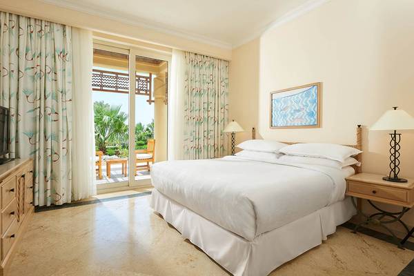 Ein elegantes Schlafzimmer im Sheraton Soma Bay Resort mit einem großen Bett, einem Balkon und einem malerischen Blick auf Palmen.