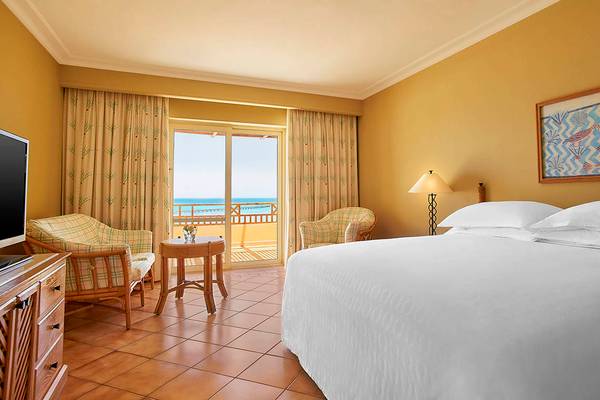 Suite-Zimmer im Sheraton Soma Bay Resort mit Meerblick, Bett, Sesseln und Fernseher.
