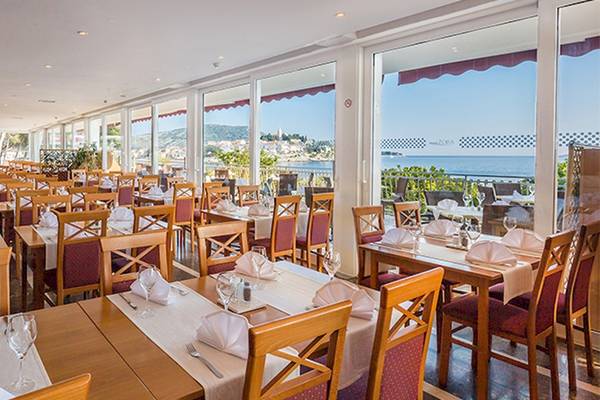 Innenansicht des Restaurants im Zora Hotel mit Blick auf das Meer und eine Reihe von gedeckten Tischen.