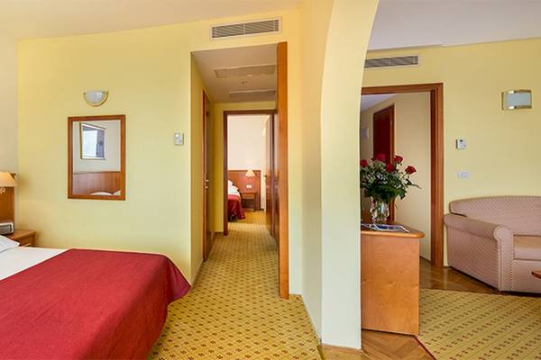 Innenansicht eines Zimmers im Zora Hotel mit Bett, Couch und gelben Wänden.