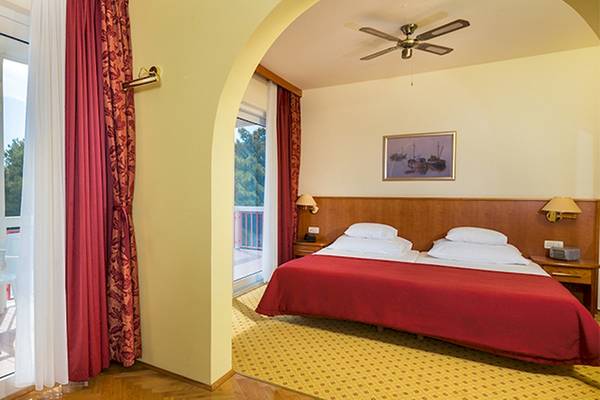 Zora Hotel Zimmer mit Balkon und Meerblick, Bett, Tisch und Stühle draußen.