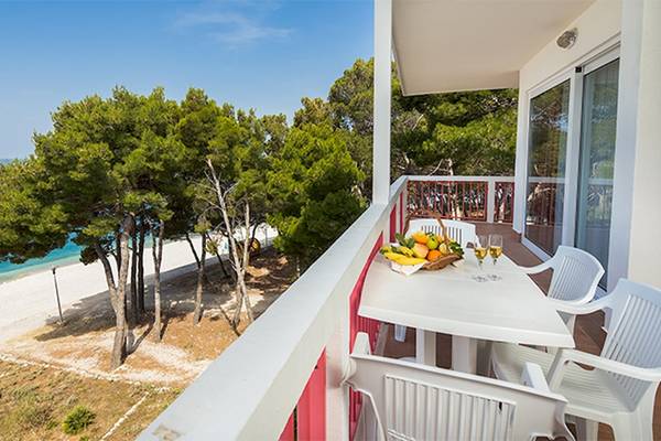Aussicht vom Balkon des Zora Hotels auf einen Strand mit einem Tisch und Früchten