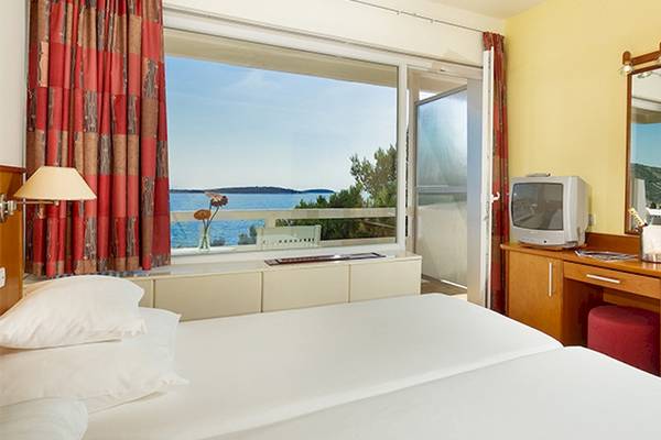 Doppelzimmer im Zora Hotel mit Meerblick, inklusive Fernseher, Schreibtisch und Blumen.