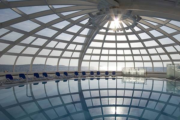 Der Poolbereich des Zora Hotels mit einer gläsernen Kuppel und Meerblick.