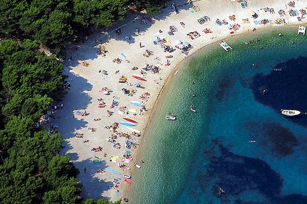 Luftaufnahme der Strandbucht des Zora Hotels, voller Besucher, die sich entspannen und schwimmen.