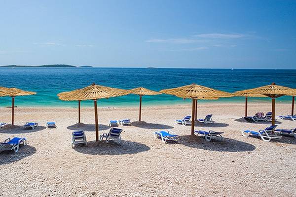 Strand mit Sonnenschirmen und Liegestühlen im Zora Hotel.