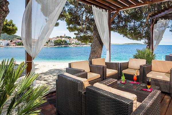 Strandterrasse des Zora Hotels mit Blick auf das Meer und eine Stadt im Hintergrund.