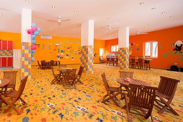 Der Kinderspielbereich im Zora Hotel mit bunten Wänden, Tischspielen und farbigen Bodenmustern.