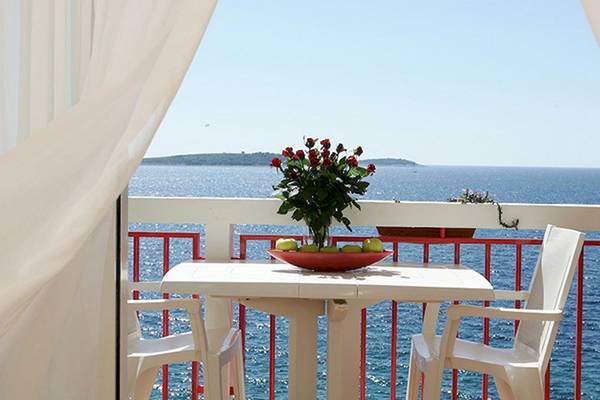 Balkon des Zora Hotels mit Tisch, Blumen und Meerblick