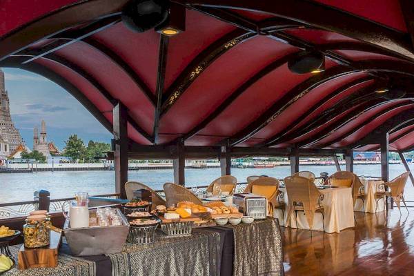Innenbereich des Anantara Riverside Bangkok Resort mit einem Buffet und Aussicht auf den Fluss und den Tempel.