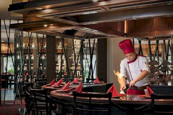 Restaurant-Interieur im Anantara Riverside Bangkok Resort mit Koch, der Essen brät
