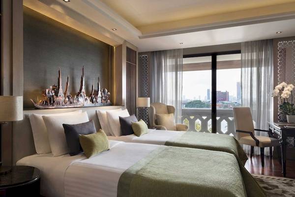 Schlafzimmer im Anantara Riverside Bangkok Resort mit zwei Betten, Dekor und Stadtblick.