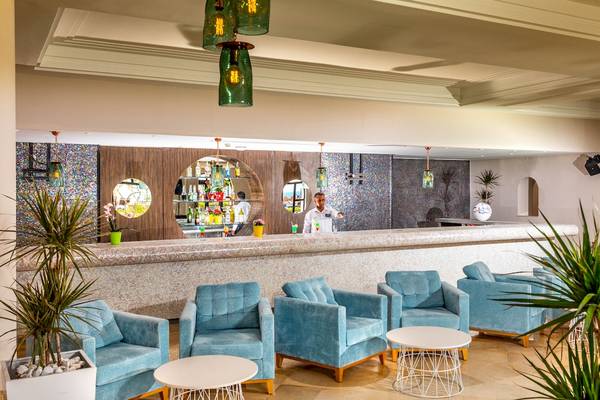 Innenansicht der Bar im Ulysse Djerba Thalasso & Spa Hotel mit Barkeeper und blauen Sesseln.