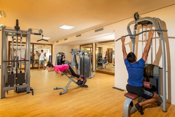 Fitnessbereich im Ulysse Djerba Thalasso & Spa mit verschiedenen Geräten und Personen beim Training.