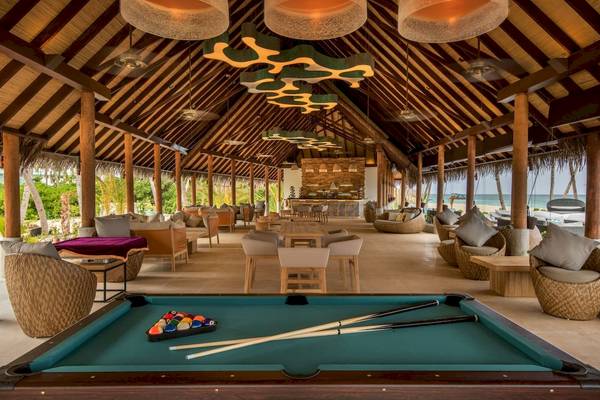 Loungebereich des Fushifaru Maldives Hotels mit Billardtisch und Strandblick.