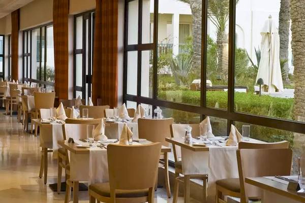 Restaurant des Ulysse Djerba Thalasso & Spa mit gedeckten Tischen und Blick auf den Garten