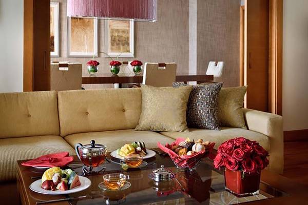 Wohnbereich des Mövenpick Hotel Jumeirah Beach mit Couch, Tisch und Essen.