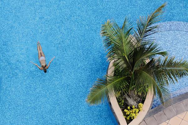 Luftaufnahme einer Person, die im Schwimmbad des Mövenpick Hotels Jumeirah Beach schwimmt.