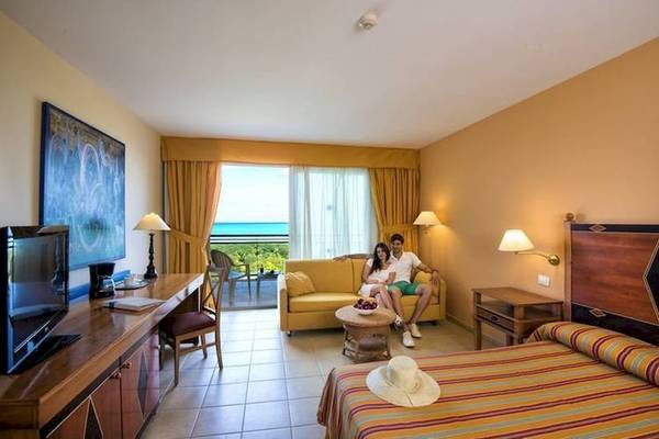 Hotelzimmer im Blau Varadero mit einem Paar auf dem Sofa, Blick auf das Meer und ein Flachbildfernseher.