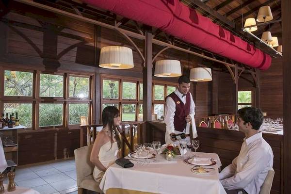Ein Paar sitzt in einem Restaurant des Blau Varadero Hotels und wird von einem Kellner bedient.