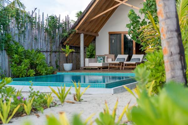Außenbereich des Fushifaru Maldives Hotels mit Pool, Loungemöbeln und Pflanzen.