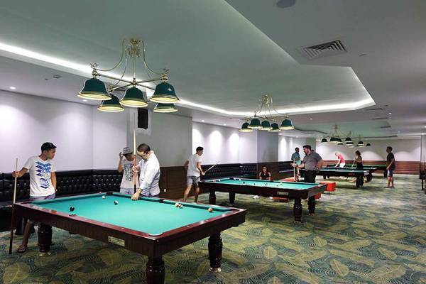 Ein Billardtisch im Sueno Hotels Deluxe Belek mit Spielern und einer gut beleuchteten Umgebung.