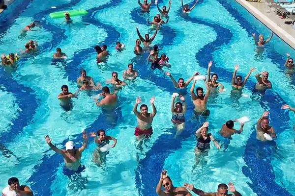 Gruppe von Menschen, die in einem Pool des Sueno Hotels Deluxe Belek schwimmen und feiern