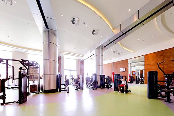 Fitness-Center im Sueno Hotels Deluxe Belek mit verschiedenen Trainingsgeräten und einer Person, die auf einem Gerät sitzt.