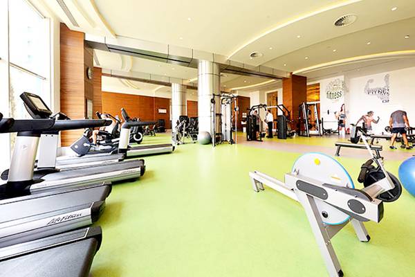 Fitnessstudio im Sueno Hotels Deluxe Belek mit Laufband, Rudergerät und Hanteln.