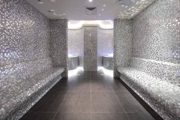Innenansicht einer Sauna im Sueno Hotels Deluxe Belek mit silbernen Mosaikfliesen und dunklem Boden.