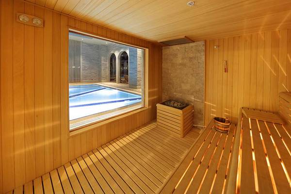 Eine geräumige Sauna mit Holzwänden und einem Fenster, das einen Pool zeigt.