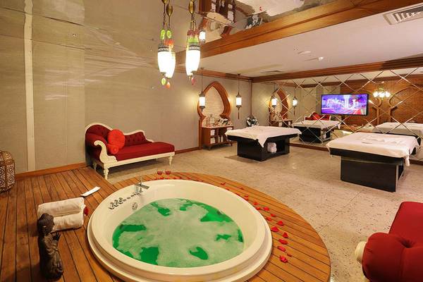 Spa-Bereich im Sueno Hotels Deluxe Belek mit großem Whirlpool, Massageliegen und Fernseher.