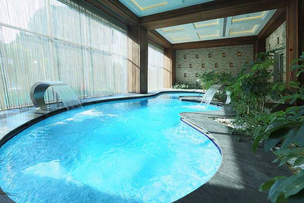 Innenpool des Sueno Hotels Deluxe Belek mit Wasserfall und Pflanzen.
