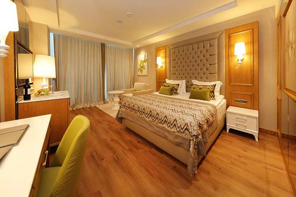 Suite-Zimmer im Sueno Hotels Deluxe Belek mit Doppelbett, Schreibtisch und Sessel.