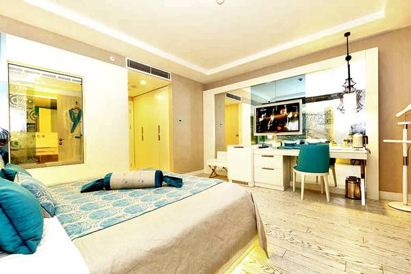 Ein modernes Hotelzimmer im Sueno Hotels Deluxe Belek mit einem großen Bett und einem Fernseher.