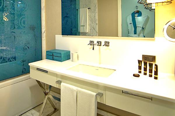 Badezimmer im Sueno Hotels Deluxe Belek mit blauen Kacheln, einer Badewanne und einem Waschbecken.