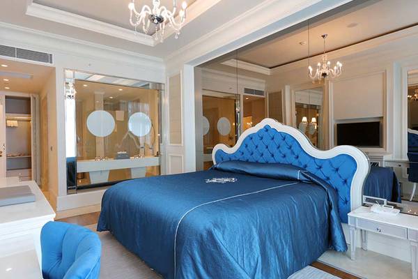 Suitenbett mit Kristallleuchter und blauer Bettwäsche im Sueno Hotels Deluxe Belek