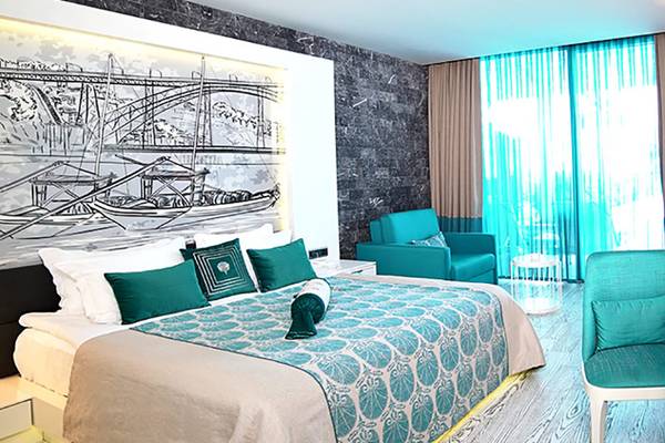 Ein Hotelzimmer im Sueno Hotels Deluxe Belek mit blauen Möbeln und einem großen Bett.