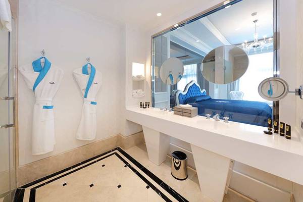 Hotelsuite Badezimmer mit Doppelbett, Spiegel und Bademantel an der Wand