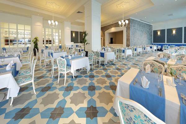 Innenansicht des Restaurants im Sueno Hotels Deluxe Belek mit blauen und weißen Tischdecken.