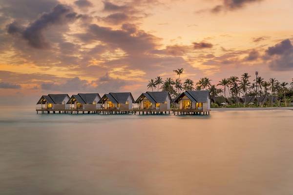 Fushifaru Maldives Hotel mit Wasserbungalows bei Sonnenuntergang
