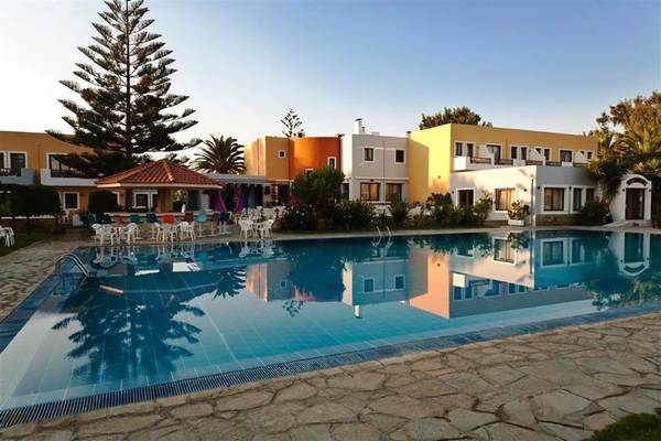Außenpool des Atlantica Marmari Beach Hotels mit farbenfrohen Gebäuden und Palmen im Hintergrund.