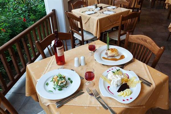 Tisch im Restaurant des Atlantica Marmari Beach Hotel mit Tellern, Wein und Dekoration.