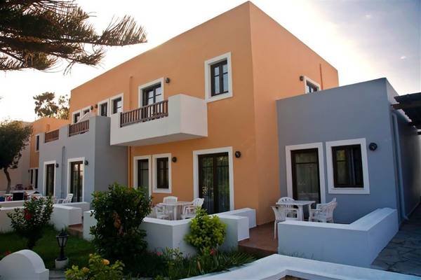 Außenbereich des Atlantica Marmari Beach Hotels mit mehreren Gebäuden, Balkonen und Tischen.